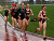 A Minnesota-Duluth runner leads Laura Edlund (r), Sarah Bernhardson (c) and Jill Fagerstrom (r) around a corner during the 5000.