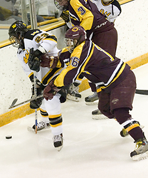 Steve Dusich (23) fights for the puck along the boards.