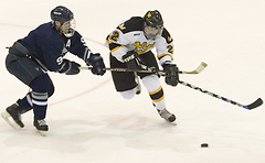 Junior John Arundel plays the puck Sophomore Tim Ornell fights through the stick of a Viking player.