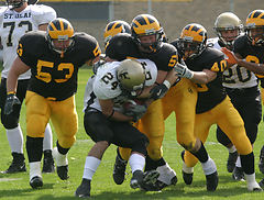 A crowd of Gustie defenders tackle a St. Olaf ball-carrier.