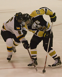 Freshman defenseman Cody Mosbeck battles with a UW-Superior defender for the puck.
