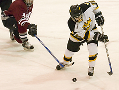 Ben Ollila handles the puck while being tripped.