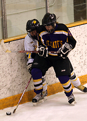 Two players fight along the boards for the puck.