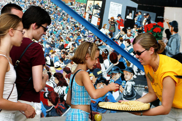 A Gustavus Ambassador passes out Gustavus three crowns cookies to young fans at a recent St. Paul Saints game.