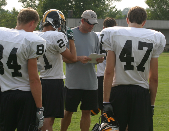 Receivers coach Tom Brown discusses formations and assignments with the receiving corps.