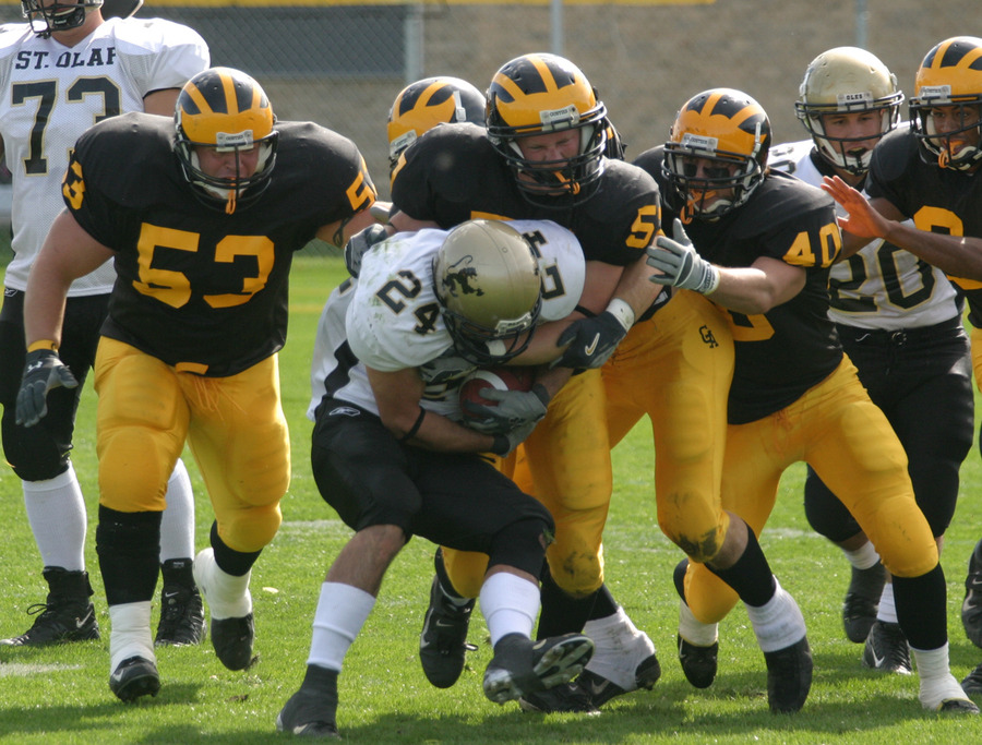 A crowd of Gustie defenders tackle a St. Olaf ball-carrier.