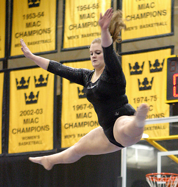Emily Pickford performs a jump high above the balance beam.