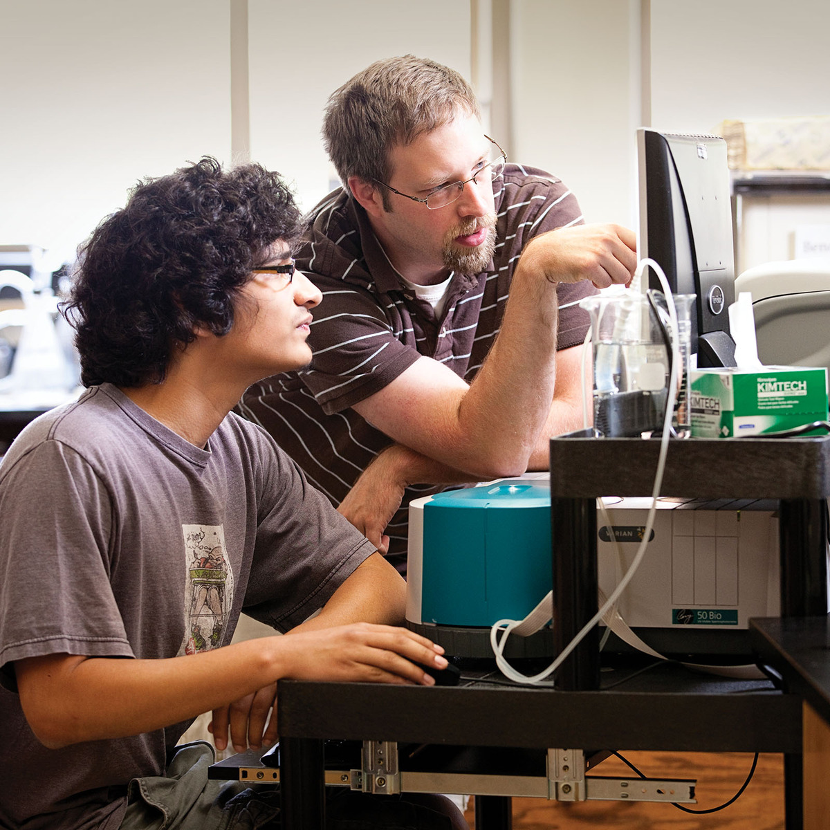 Instructor and student reviewing lab results at a computer screen.