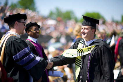 Gustie graduate shaking hands at commencement.