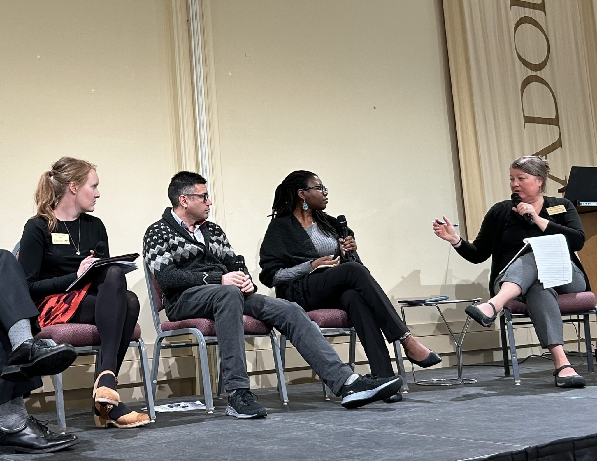 Faculty members engage in a panel discussion on stage, with one honored for outstanding teaching with the Swenson-Bunn Award.
