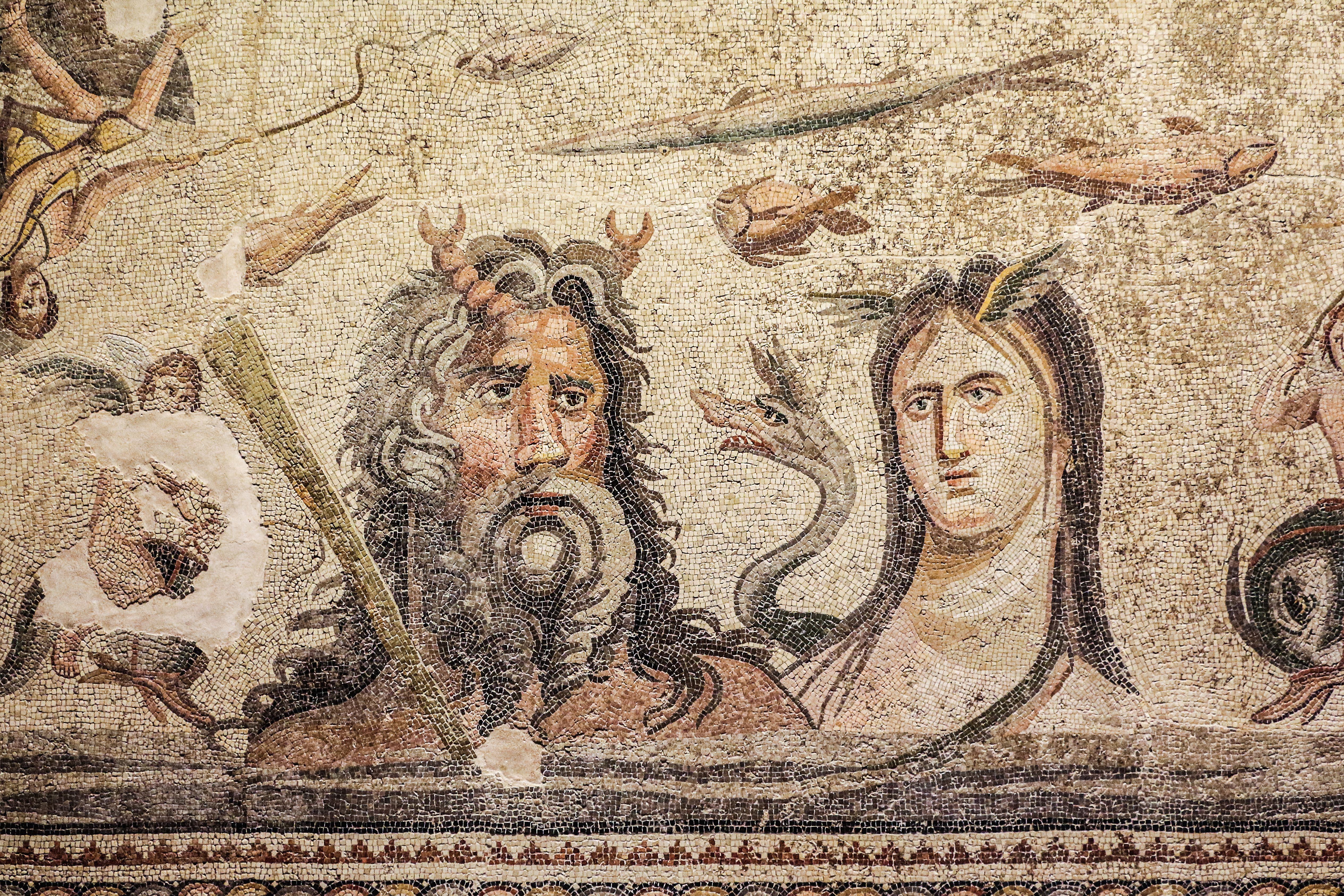 A male god with horns, long hair and beard and a long haired goddess with wings growing from her temples surrounded by fish
