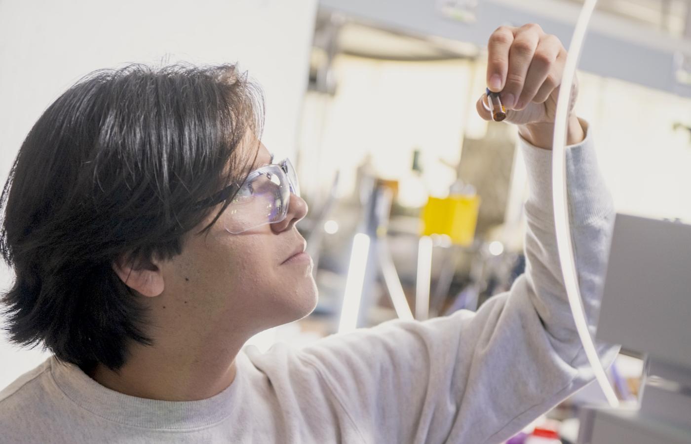 A student in goggles inspects a specimen. 