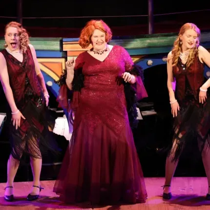 Several performers dance to a musical number in glittery gowns. 