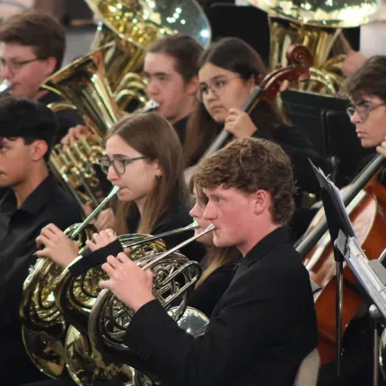Students in the Gustavus Wind Orchestra performing on brass and string instruments in Christ Chapel.