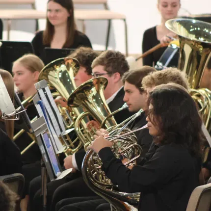Students in the Gustavus Wind Symphony performing on brass and string instruments in Christ Chapel.
