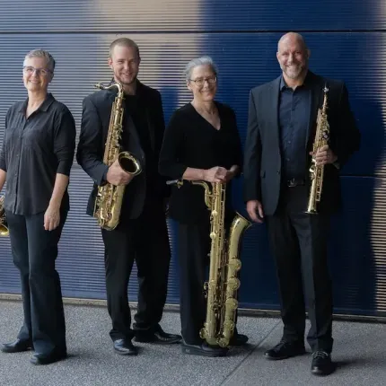 Four members of the Ancia Quartet in concert black, holding various types of saxophones.