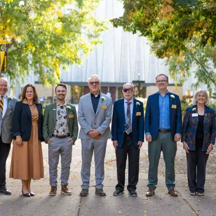 Group of seven alumni standing in front of Christ Chapel