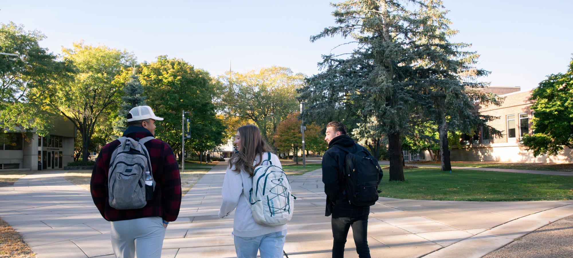 3 students on Eckman Mall and Carlson Administration Building