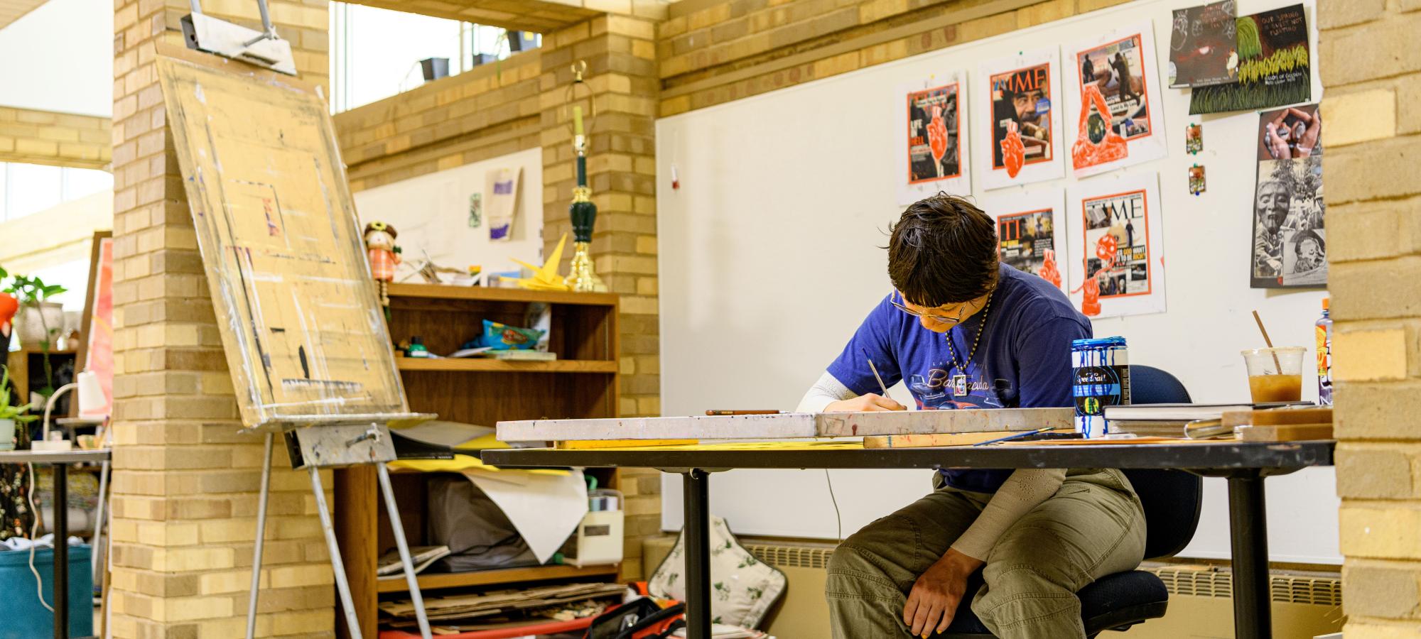 Student drawing at table in Art Building