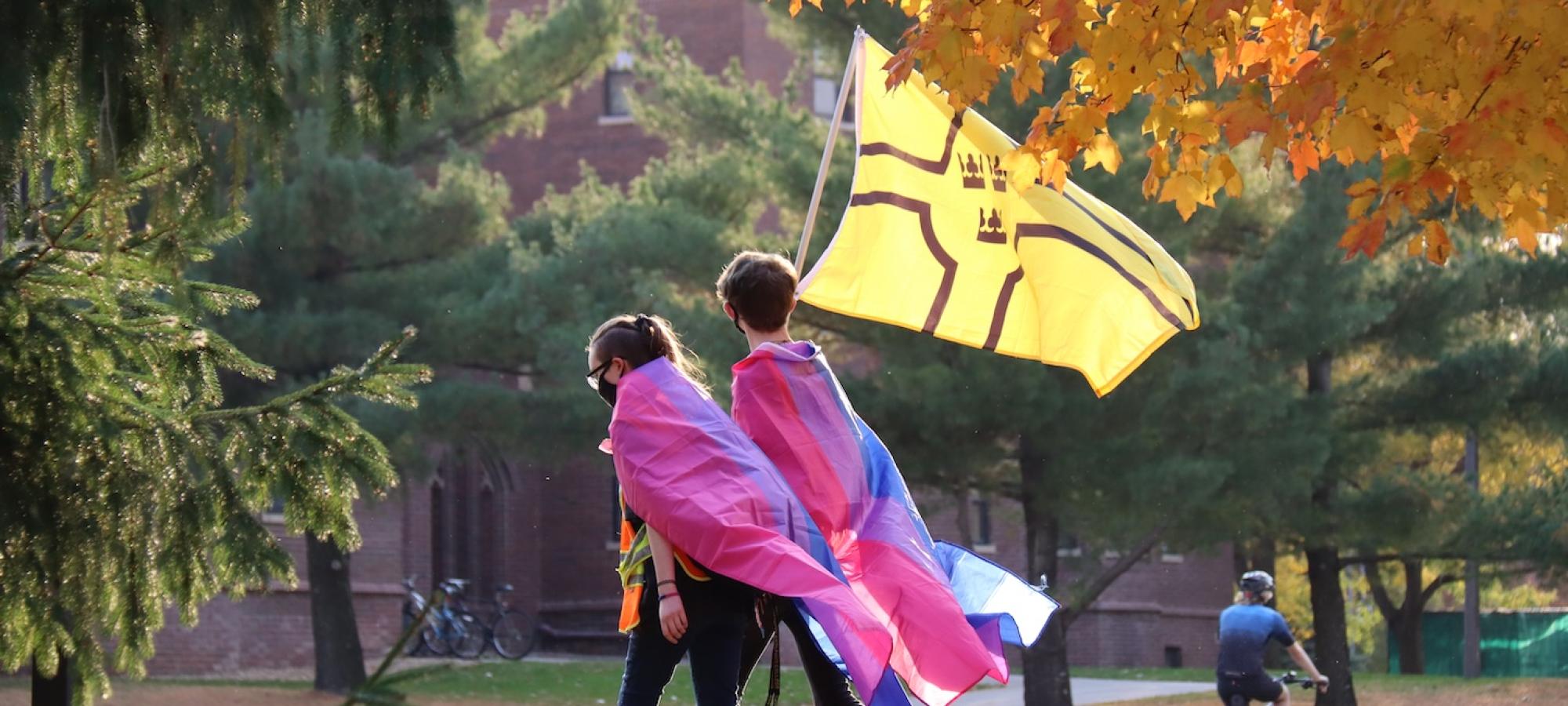 Students walk through a campus with various flags. 