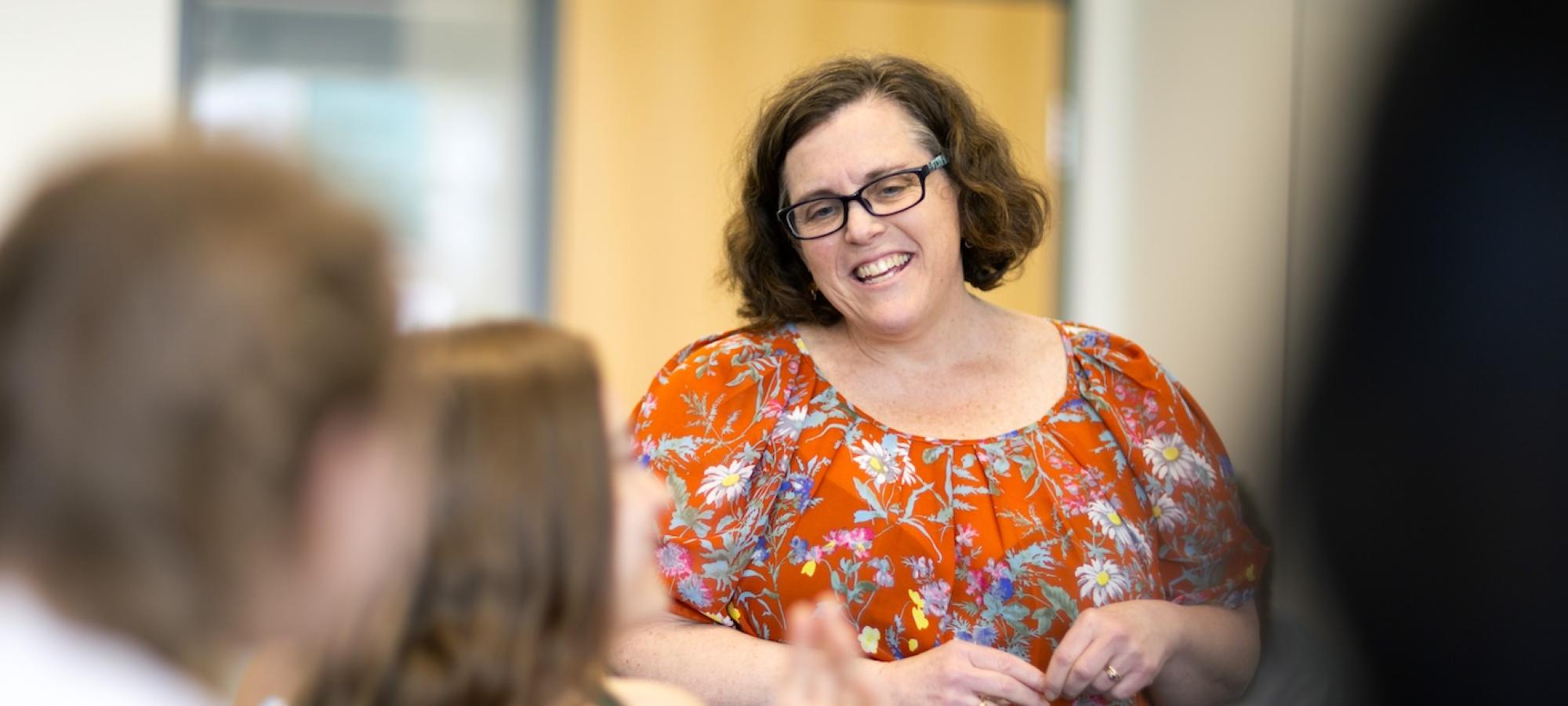 A professor smiles at students. 