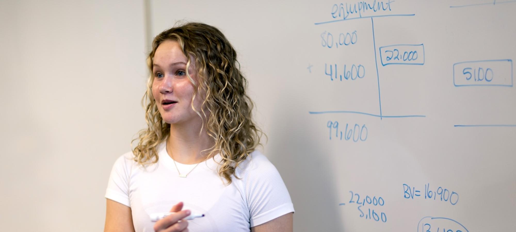 A young woman shows her work in an Economics class. 