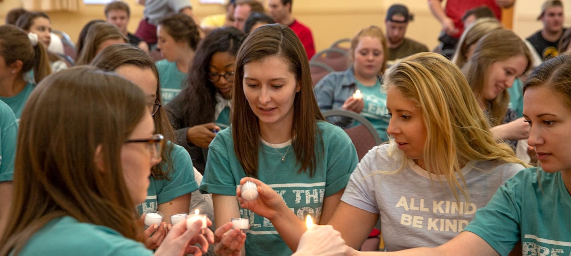 Students with candles and t-shirts that say Break the Silence. 