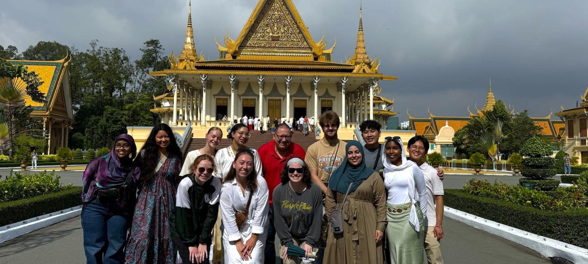 Students and professors stand before a temple. 