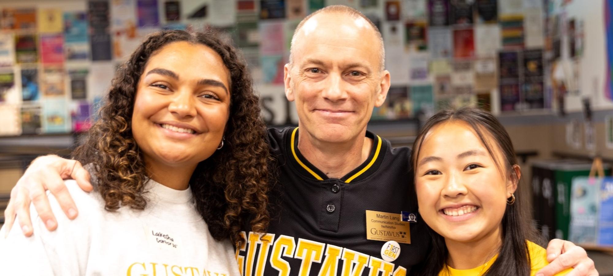 A man and two students smile at the camera. 