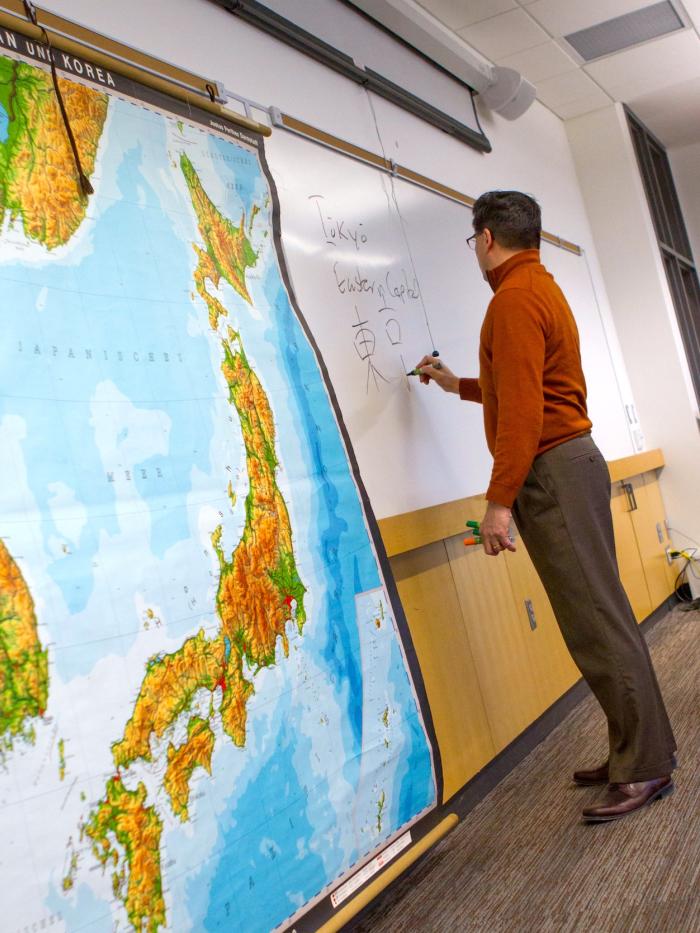 A Gustavus Adolphus Professor stands with a map of Japan. 